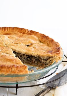 a pie sitting on top of a glass plate with a slice missing from it's crust