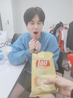 a young boy holding a bag of diapers in front of someone's face