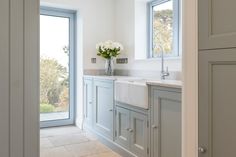 a white kitchen with gray cabinets and an open door that leads to the outside patio