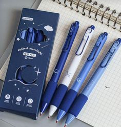 four pens sitting next to each other on top of a notepad with a pen in it