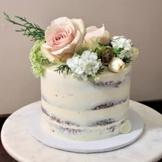 a white cake with flowers and greenery on top