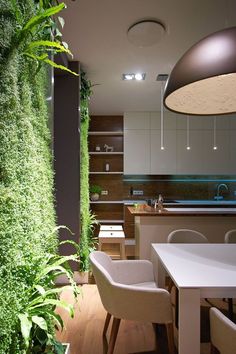 the interior of a modern kitchen with plants growing on the wall and dining room table