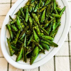 a white bowl filled with green beans on top of a table