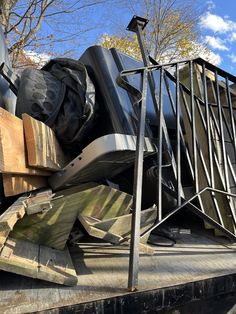 a pile of wood sitting on the back of a dumpster next to a tree