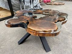 a table made out of wood with metal legs and a glass top on the ground