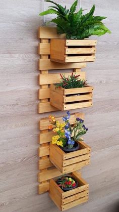 three wooden planters with plants in them hanging on the wall next to a potted plant