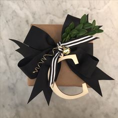 a gift wrapped in black and white ribbon with a gold letter on the front that says c