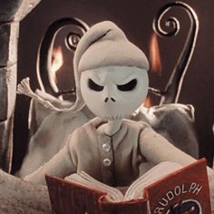 a creepy doll is reading a book while sitting in a chair with an open book