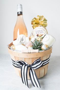 a bottle of wine sitting next to a basket filled with cheese and other food items