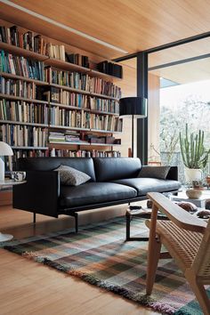 a living room filled with furniture and bookshelves next to a wooden floor covered in plants