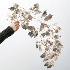 a person is holding leaves in the air with their hand and fingers, while they are flying through the air