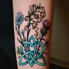 a tattoo with flowers and an intertwined knot on the arm, which is blue