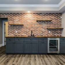 an empty kitchen with wooden floors and brick wall