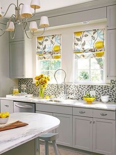 a kitchen with white cabinets and yellow flowers in the window sill next to the sink