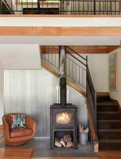 a living room with a fire place next to a stair case and a leather chair