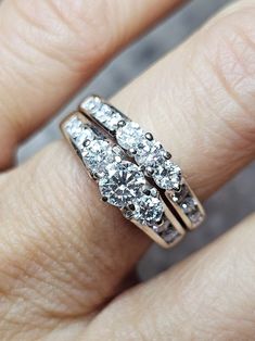 a woman's hand with a diamond ring on top of her finger and two diamonds in the middle