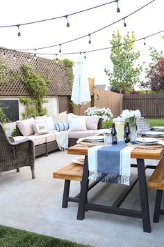 an outdoor dining area with patio furniture and string lights strung over the back yard table