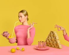 a woman sitting at a table with food in front of her and holding a straw