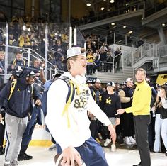 a man holding a football on top of a ice rink next to people in the stands