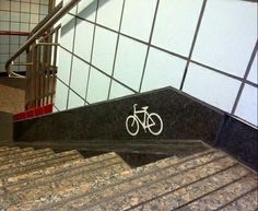 there is a bike sign on the wall next to the stairs in this public restroom