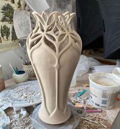 a vase sitting on top of a table covered in paint and paper work next to a painting easel