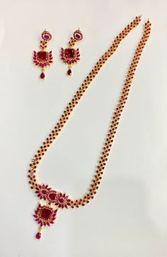 **Elegant Ruby Floral Necklace Set** - **Polish 22k Gold Plated, providing a rich and luxurious finish that enhances the vibrant red stones. - **Stones Beautiful ruby-colored simulated stones are arranged in a floral pattern, creating a delicate and elegant look. - **Design The necklace features intricate detailing with ruby stones set in a floral and geometrical pattern, along with matching earrings that complete the set. The design is perfect for special occasions and traditional events. - **Style Indian Traditional Jewelry - Perfect for weddings, festive events, and formal functions. - **Dimensions    - **Necklace Length 12 inches (plus an adjustable back chain).   - **Earring Length 6 cm. - **Handmade Crafted with precision, this set is a piece of fine artisan work, featuring hand-set Red Gold-plated Jewelry Set For Wedding, Elegant Red Necklaces For Festivals, Red Jewelry Sets For Formal Festivals, Red Stone Setting Bridal Necklace As Gift, Elegant Red Jewelry Sets For Festive Occasions, Red Gold Plated Necklaces For Wedding, Ruby Jewelry Sets For Party And Festivals, Red Kundan Necklace For Formal Temple Jewelry Style, Formal Red Jewelry Sets With Stone Work