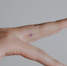 a person's hand with a tiny star tattoo on the left side of their arm