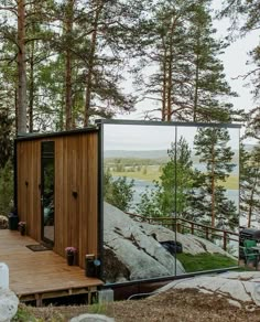 a small wooden cabin in the middle of a forest with a large mirror on it's side