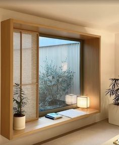 a living room filled with furniture and a large window covered in blinds next to a potted plant