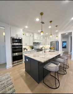 a large kitchen with an island in the middle and four stools at the end