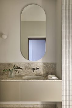 a bathroom sink with a mirror above it and a vase on the counter next to it