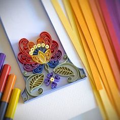 an assortment of colored crayons and markers on a table with a paper flower