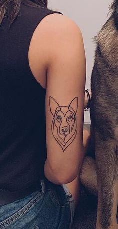 a woman with a tattoo on her arm next to a large brown and black dog