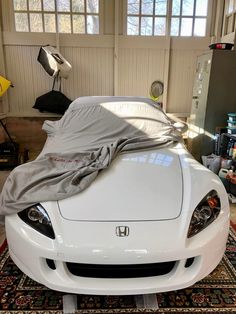 a white sports car covered with a sheet in a garage