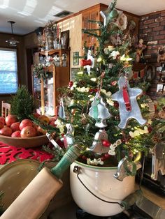 a decorated christmas tree in a kitchen next to a bowl of apples and other holiday decorations