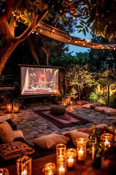 an outdoor movie screen surrounded by candles and trees