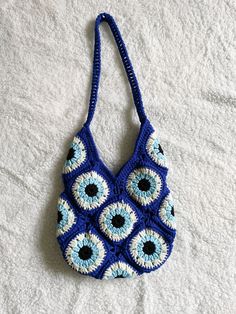 a crocheted bag with an evil eye pattern on it sitting on a bed