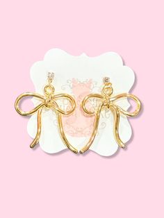 Evie Gold Bow Earrings | Sassy Shortcake |sassyshortcake.com Chic Gold Earrings With Decorative Bow, Chic Gold Earrings With Bow, Gold Earrings With Decorative Bow As Gift, Chic Bow Drop Earrings, Feminine Bow Drop Earrings Jewelry, Gold Dangle Jewelry With Bow, Cute Bow Jewelry For Parties, Cute Bow Earrings For Wedding, Cute Gold Bow Earrings