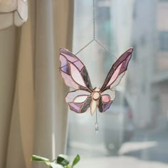 a stained glass butterfly hanging from a window