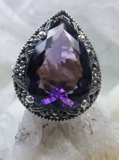 Natural Amethyst Gemstone Teardrop RingTear Vic Design#D28 Inspired by Victorian and Art Deco designs, this high-quality filigree ring is handcrafted in sterling silver. This teardrop ring is set with an 8.37 carat pear cut flawless natural purple amethyst gemstone. The gem is 16mm (~5/8") x 12mm (~1/2"). The gorgeous stones have lovely vibrant color. The inside of the band is marked 925 for sterling silver. Notice the beautiful filigree of the silver setting. This is a ring with beauty and grac Formal Teardrop Amethyst Ring, Elegant Teardrop Amethyst Gemstone Ring, Elegant Silver Teardrop Amethyst Ring, Teardrop Amethyst Ring For Anniversary, Elegant Teardrop Amethyst Ring, Elegant Teardrop Amethyst Ring Gift, Teardrop Amethyst Ring As Gift, Teardrop Amethyst Ring For Gift, Ornate Sterling Silver Amethyst Gemstone Ring