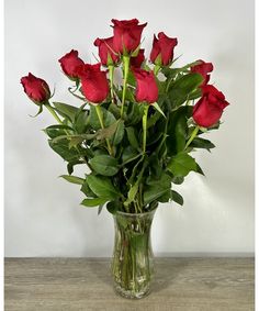 a vase filled with red roses on top of a wooden table