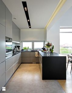 a modern kitchen with stainless steel appliances and black counter tops, along with large windows