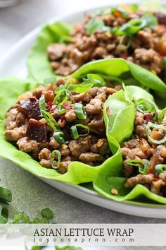 lettuce wraps filled with meat and vegetables on a white plate, ready to be eaten