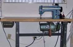 a sewing machine sitting on top of a wooden table next to a ruler and threading needles