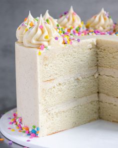 a cake with white frosting and sprinkles is cut from the side