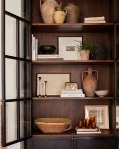 a wooden shelf with vases and books on it