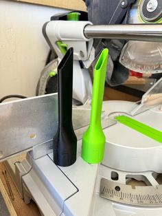 a green object is sitting on top of a workbench with a measuring tool next to it