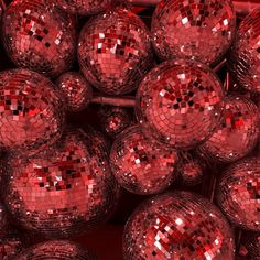 many shiny red disco balls are stacked together in a bin with one ball facing the camera