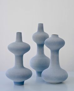 three blue vases sitting next to each other on top of a white countertop