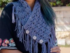 a woman with green hair is wearing a blue knitted shawl and smiling at the camera